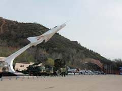 An overview of the outside display of the China Aviation Museum, on pole Nanchang J-12  in the back the tunnel with aircraft on display.